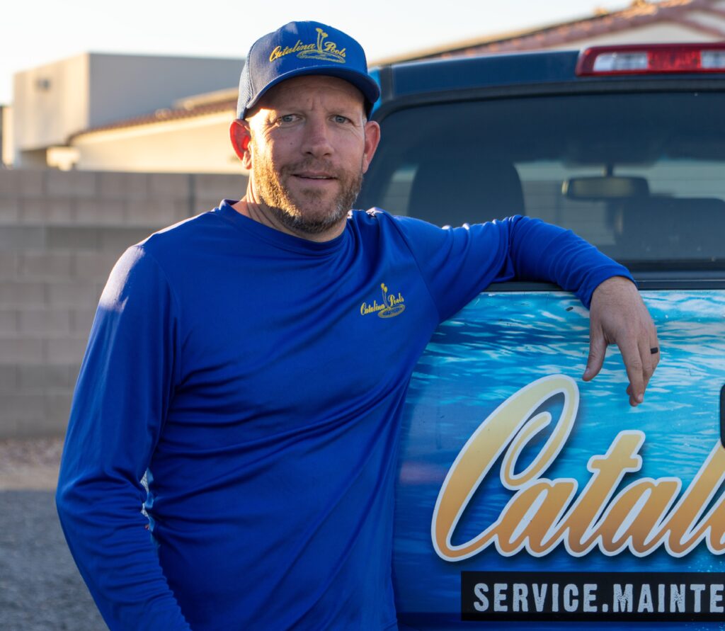 Catalina Pools AZ employee leans on his work truck outside of a client site.